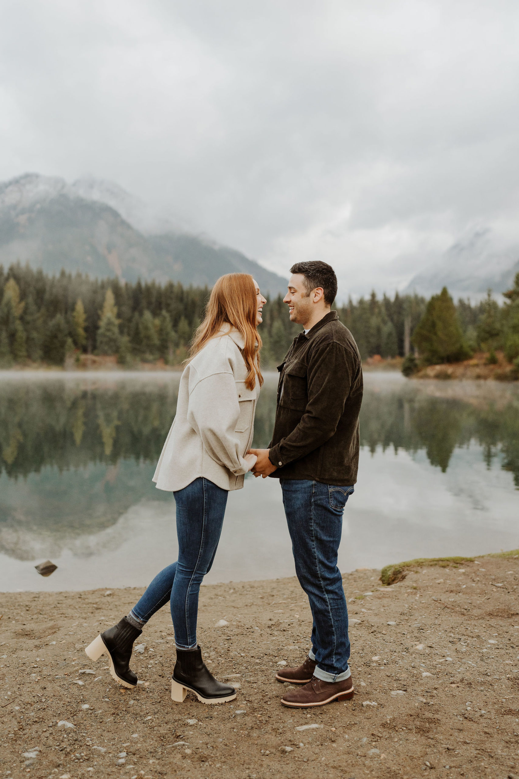 couple holding hands laughing at Gold Creek Pond for their engagement